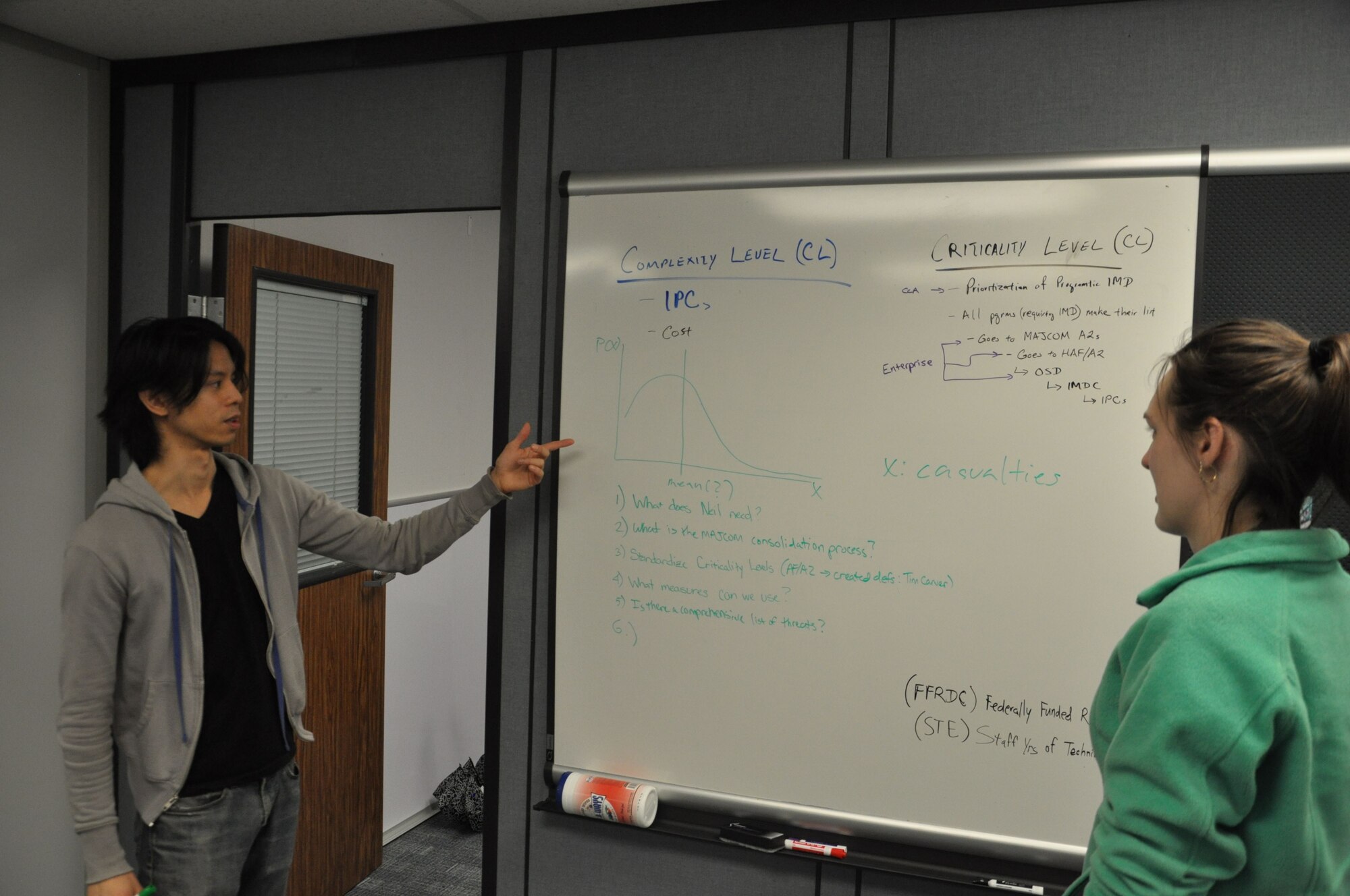 Franco Villongco, (left) an operations research analyst with the Air Force Life Cycle Management Center headquartered here, confers with colleague Brittany Elliott about a research model he developed. (U.S. Air Force photo / Brian Brackens)