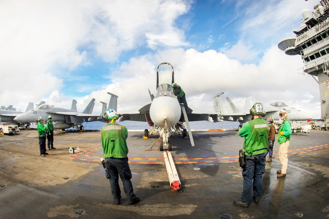 Sailors perform maintenance on an F/A-18E Hornet aircraft.