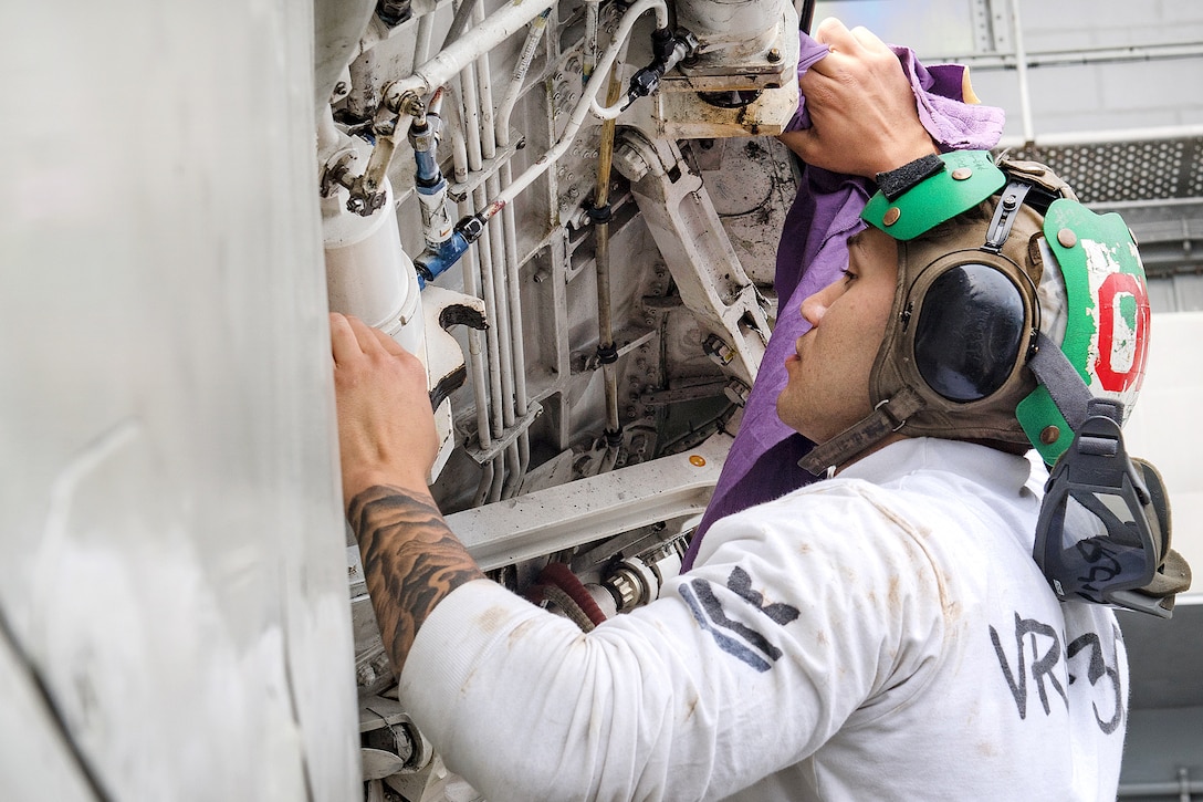 A sailor performs maintenance on a C-2A Greyhound aircraft.