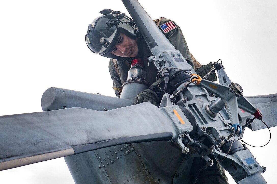 A sailor performs final checks on a MH-60R Seahawk helicopter.