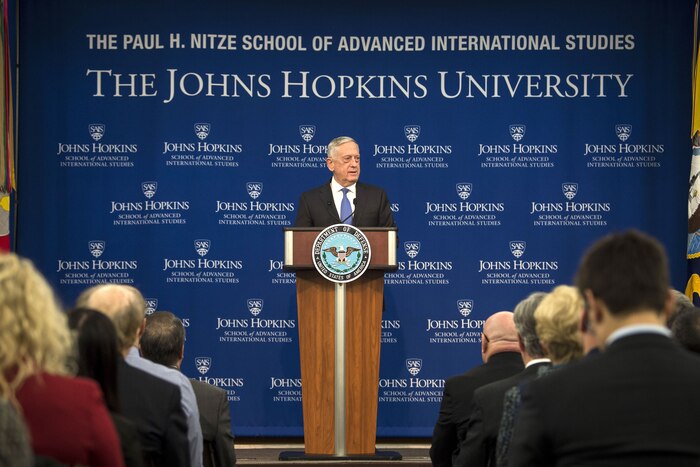 Defense Secretary James N. Mattis stands behind a podium speaking to a group of people.