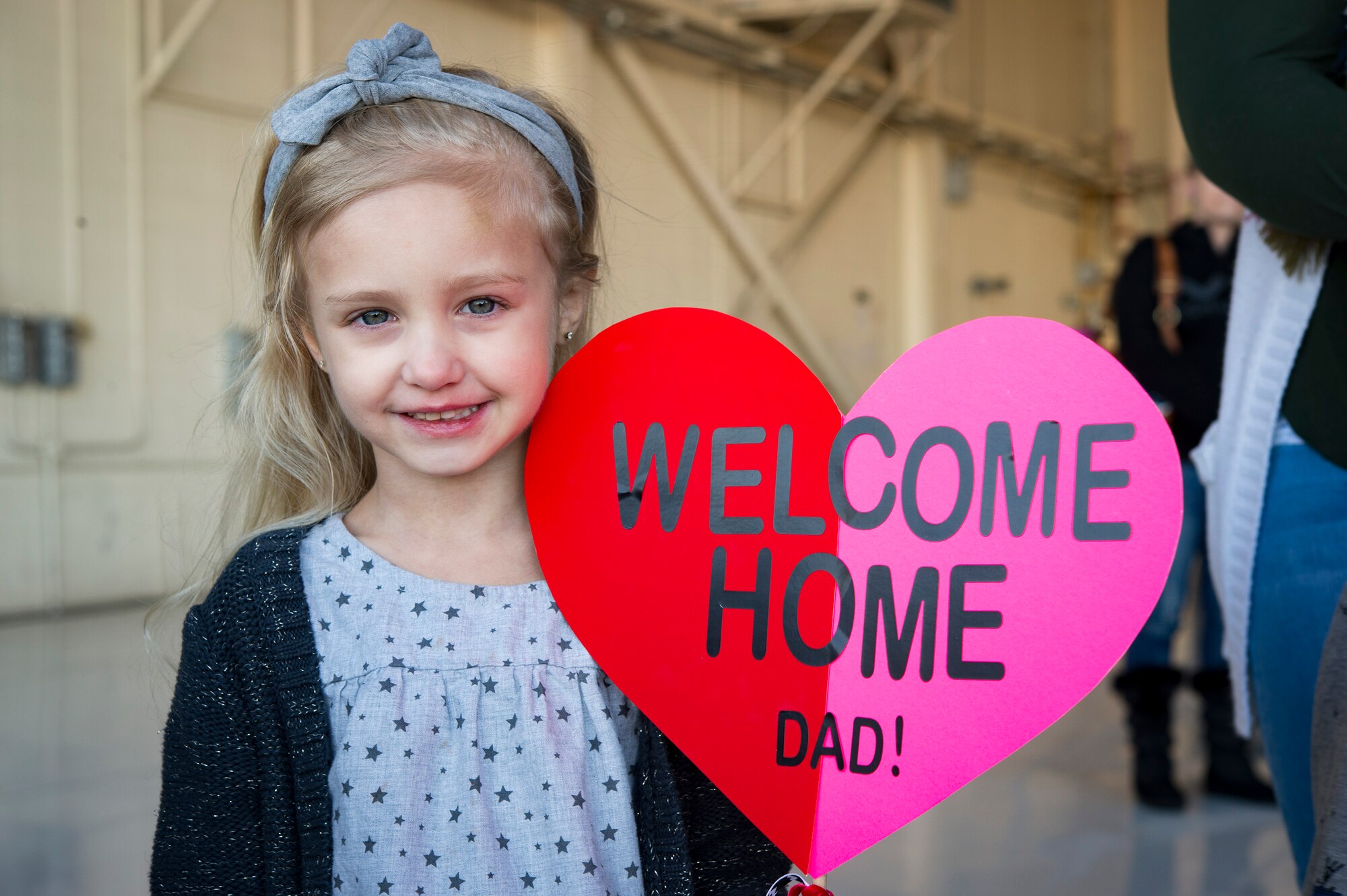 A child poses with her hand made sign for a photo during a redeployment ceremony for the 74th Fighter Squadron, Jan. 19, 2018, at Moody Air Force Base, Ga. Over 300 Airmen from Team Moody deployed for seven months in support of Operation Inherent Resolve to defeat ISIS in designated areas in Iraq and Syria. (U.S. Air Force photo by Andrea Jenkins)