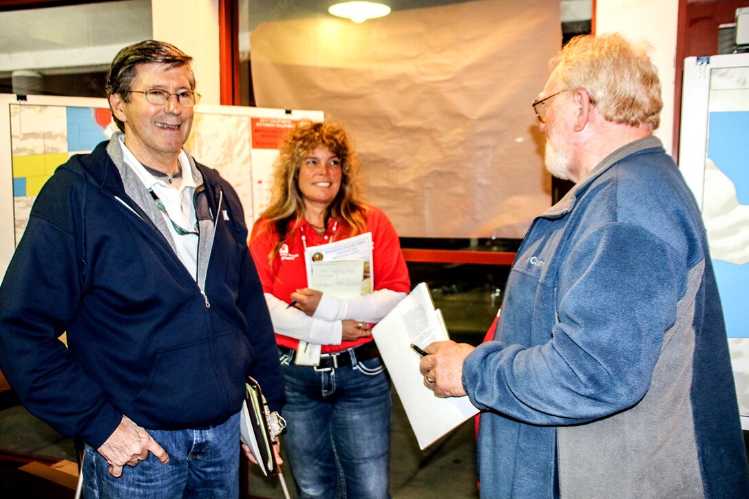 Moe Adams (center), resident engineer at the Emergency Field Office in Redwood Valley, and Norbert Suter (left), chief of Operations Section at the Sonoma Recovery Field Office, spoke with a resident during the Mendocino County Community meeting on Jan. 17.