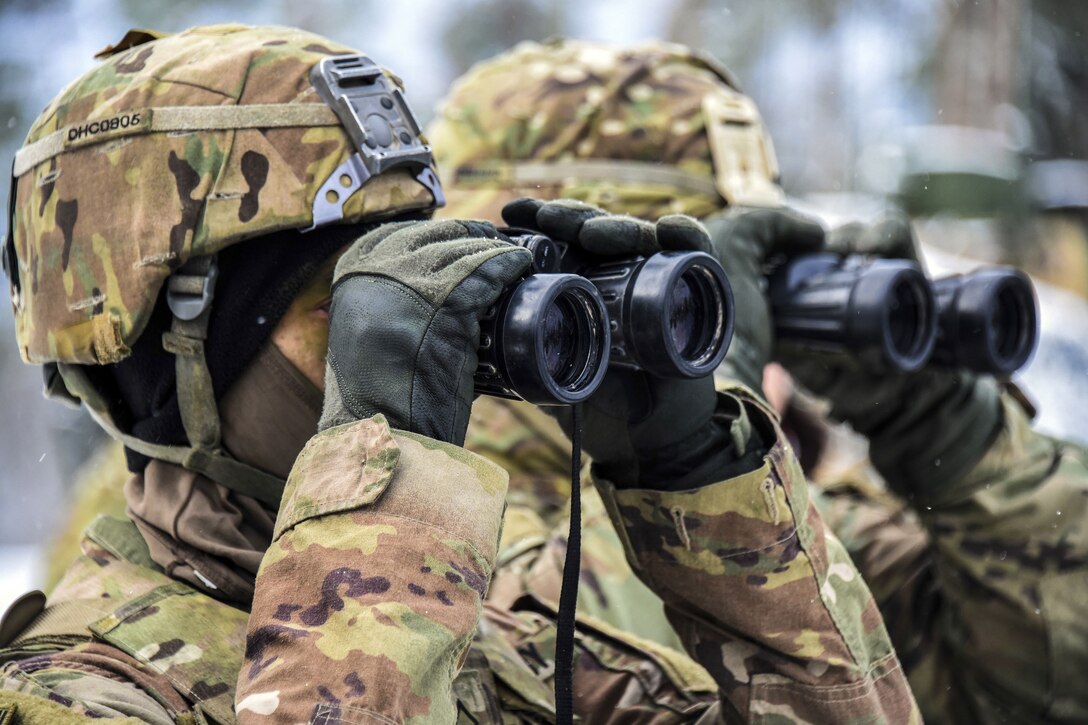 Two soldiers look through binoculars.