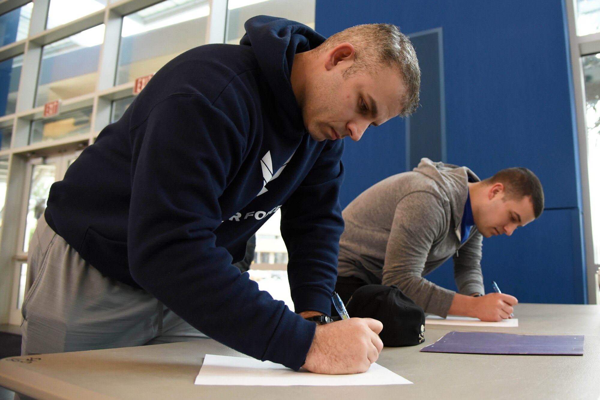 Tech. Sgts. Raymond Santiago and Zane Williams, Mathies NCO Academy students, sign in to volunteer for a food drive at the Mississippi Coast Coliseum and Convention Center Jan. 16, 2018, Biloxi, Mississippi. More than 80 Airmen participated in the wing-level community sponsored volunteer event packaging over 21,000 pounds of food, equating to approximately 17,500 meals that will be provided to hunger relief. (U.S. Air Force photo by Kemberly Groue)