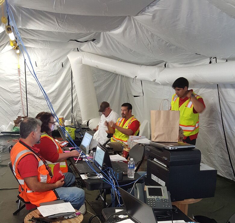 U.S. Army Corps of Engineers, Walla Walla District, temporary emergency power team members discuss their mission Nov. 25, 2017, in “the office” -- a tent at FEMA’s Incident Support Base on St. Croix, U.S. Virgin Islands. (left to right) Shawn McCann, quality assurance representative; Mary VanSickle, contract specialist; Rich Hilt, power subject matter expert; Don Redman, mission manager; Carlos Flores Lopez, quality assurance representative.