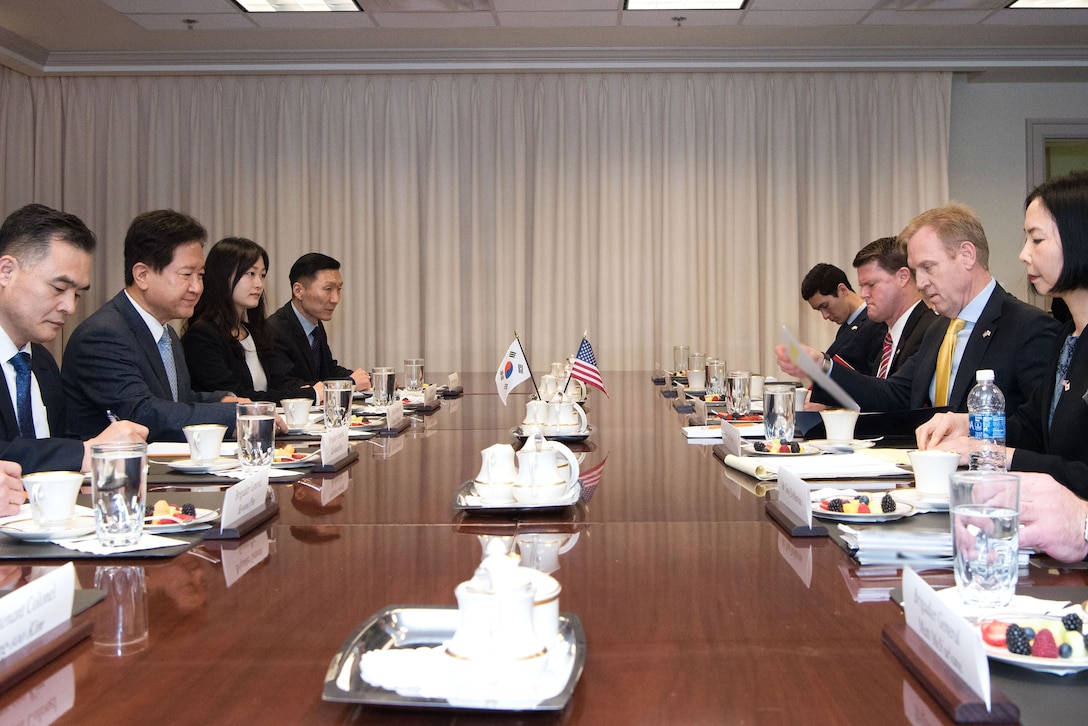 The deputy defense secretary sits at a table with other people.