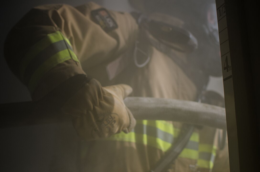 Airmen assigned to the 380th Expeditionary Civil Engineer Squadron fire department, carry a fire hose into a simulated building fire at Al Dhafra Air Base, United Arab Emirates, Jan. 12, 2018. The training evaluated firefighters on extinguish a fire and rescuing a victim in the area while applying firefighting procedures. (U.S. Air National Guard photo by Staff Sgt. Colton Elliott)