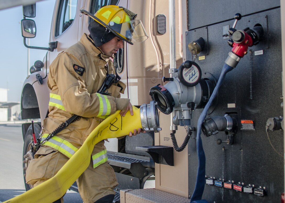 U.S. Air Force Airman 1st Class Jacob Bull, 380th Expeditionary Civil Engineer Squadron firefighter, connects a supply line to a fire truck at Al Dhafra Air Base, United Arab Emirates, Jan. 12, 2018. The firefighters were being evaluated on extinguishing a two-story structural fire. (U.S. Air National Guard photo by Staff Sgt. Colton Elliott)