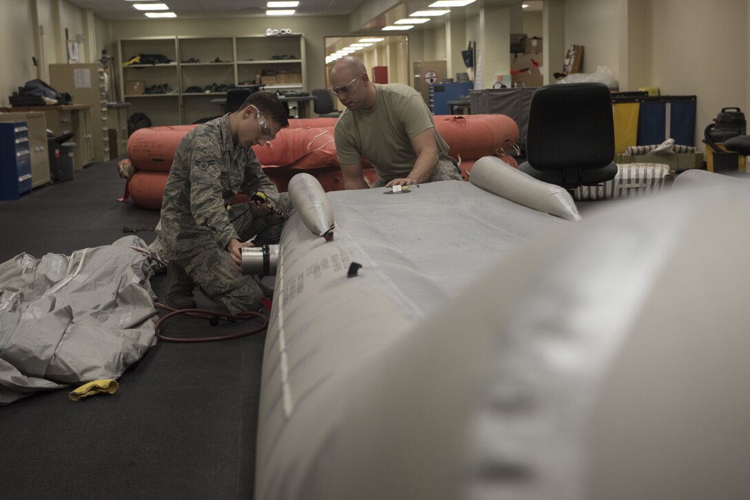 U.S. Air Force Airman 1st Class Joshua Brewer, 18th Operation Support Squadron aircrew flight equipment apprentice, and Staff Sgt. Brandon McDaniels, 18th OSS aircrew flight equipment craftsman, inspect an aircraft slide Jan. 18, 2018, at Kadena Air Base, Japan. AFE Airmen are responsible for inspecting and testing survival equipment for various aircraft on base. (U.S. Air Force photo by Staff Sgt. Micaiah Anthony)