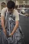 U.S. Air Force Senior Airman Alex Espinoza, 31st Rescue Squadron aircrew flight equipment technician, packs an advanced ram air parachute system Jan. 18, 2018, at Kadena Air Base, Japan. AFE Airmen must follow specialized packing procedures and conduct an extensive series of safety checks for each parachute. (U.S. Air Force photo by Staff Sgt. Micaiah Anthony)