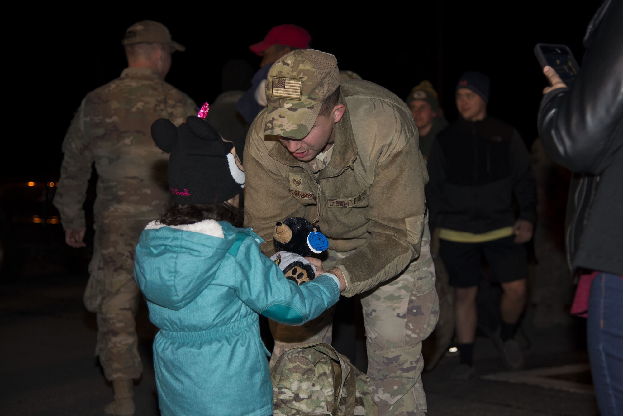 Staff Sgt. Justin Stevenson, 436th Security Forces Squadron defender, hands a stuffed animal to his daughter, Julia, Jan. 21, 2018, at Dover Air Force Base, Del. Stevenson and 11 of his wingmen returned early that morning from a six-month deployment to the Middle East. (U.S. Air Force Photo by Staff Sgt. Aaron J. Jenne)