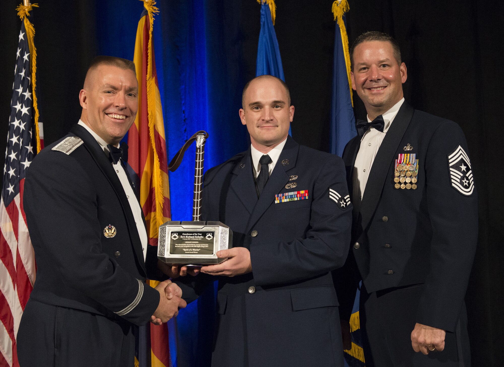 Senior Airman Richard Schultz, 61st Aircraft Maintenance Unit F-35 integrated avionics journeyman, receives the Guardsman of the Year Award from Brig. Gen. Brook Leonard, 56th Fighter Wing commander and Chief Master Sergeant Randy Kwiatkowski, 56th FW command chief, at the 2017 Annual Awards Banquet in Litchfield Park, Ariz., Jan. 20, 2018. The banquet was held to recognize and award the top performing Airmen from Luke Air Force Base. (U.S. Air Force Photo/Airman 1st Class Alexander Cook)