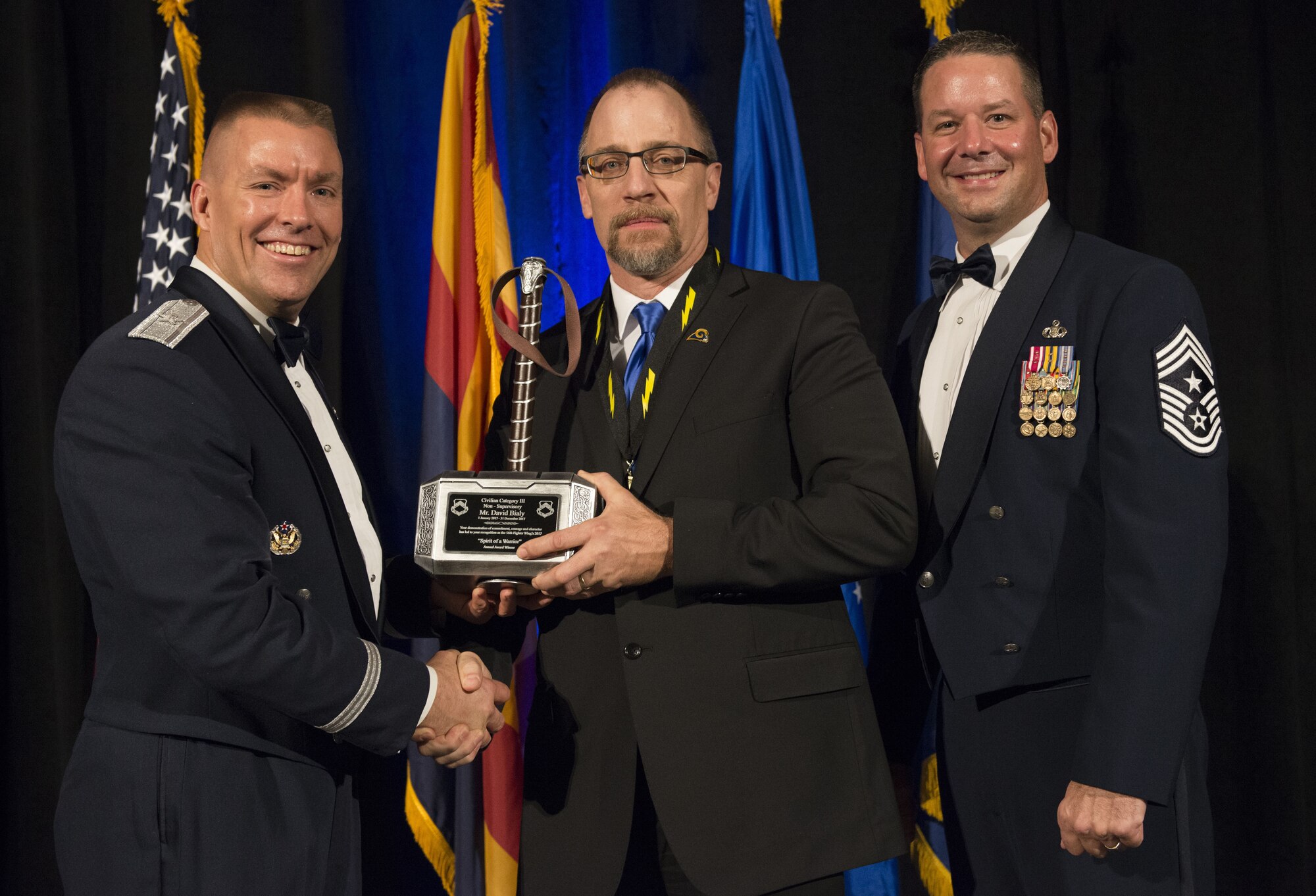 David Bialy, 56th Communications Squadron communications security manager, receives the Category III Non-Supervisory Award from Brig. Gen. Brook Leonard, 56th Fighter Wing commander and Chief Master Sergeant Randy Kwiatkowski, 56th FW command chief, at the 2017 Annual Awards Banquet in Litchfield Park, Ariz., Jan. 20, 2018. The banquet was held to recognize and award the top performing Airmen from Luke Air Force Base. (U.S. Air Force Photo/Airman 1st Class Alexander Cook)