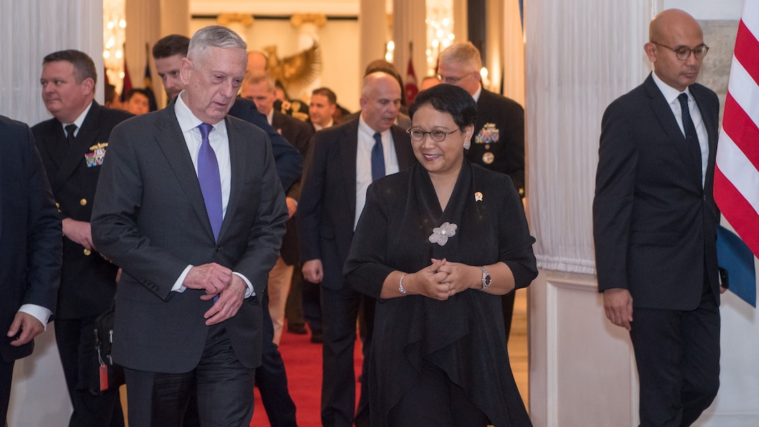 Defense Secretary James N. Mattis walks with Indonesia's foreign minister, followed by a group of people.