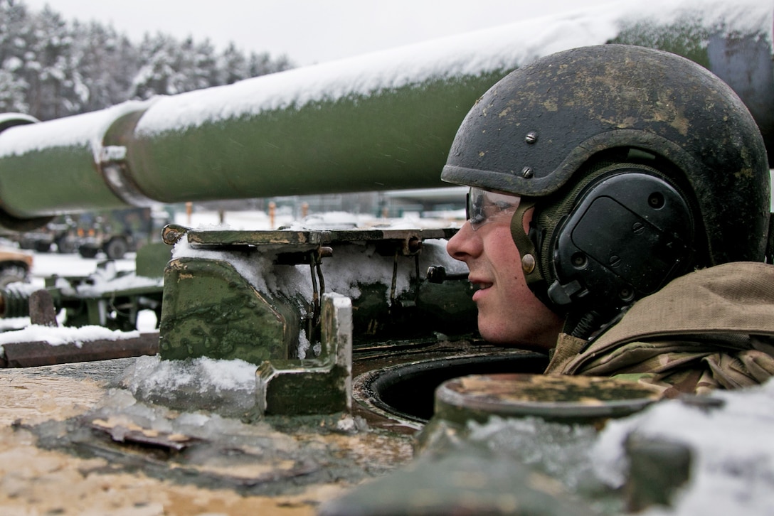 A soldier looks off into the distance as he starts a vehicle from below.