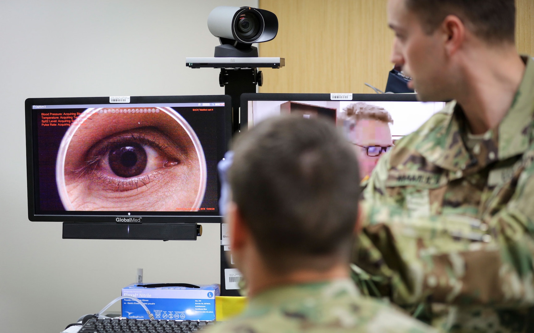 In a demonstration of the Telehealth process at Fort Campbell's Blanchfield Army Community Hospital, clinical staff nurse Lt. Maxx P. Mamula examines patient Master Sgt. Jason H. Alexander using a digital external ocular camera. The image is immediately available to Lt. Col. Kevin A. Horde, a provider at Fort Gordon's Eisenhower Medical Center, offering remote consultation.