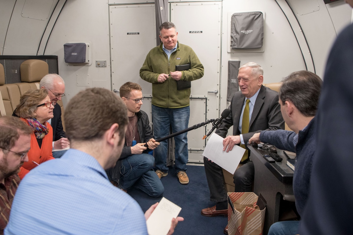Defense Secretary James N. Mattis sits on a plane speaking to people with recorders.