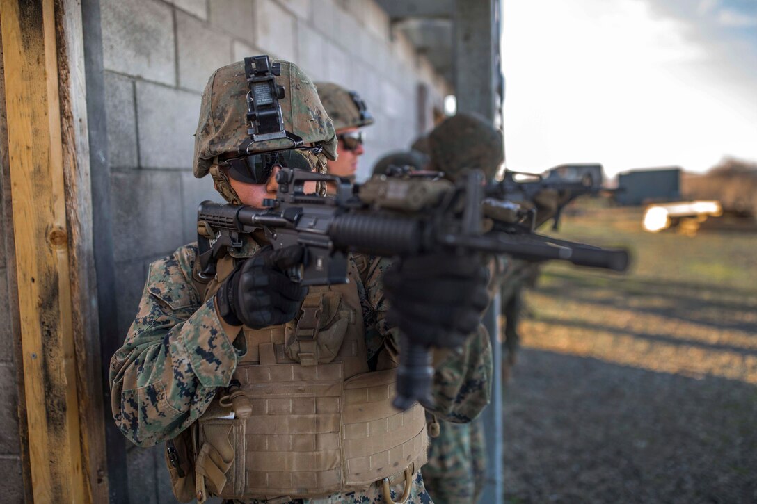 A Marine provides security while his team members set explosives on a door.