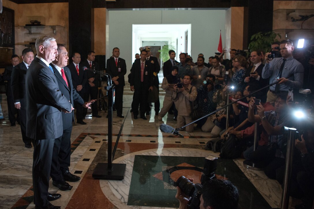 Defense Secretary James N. Mattis shakes hands with the Indonesian defense minister in front of the media.
