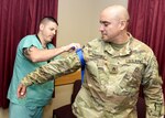 Chris Bell places a tourniquet on Staff Sgt. Luis Sanchez during a training session designed to train instructors to conduct classes for U.S. Army Institute of Surgical Research staff members on “Stop the Bleed.”