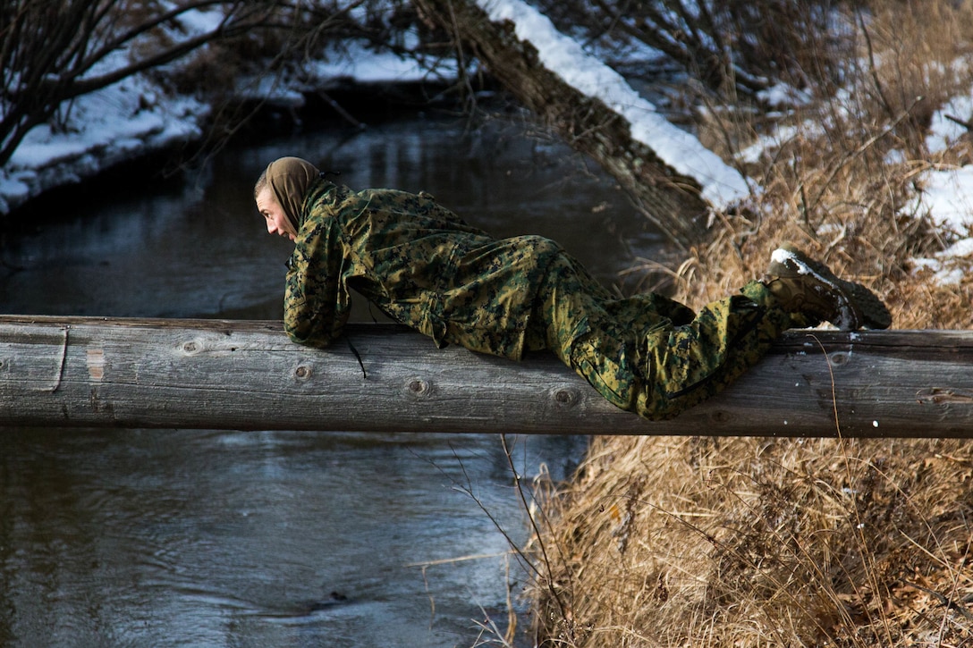 A Marine lays on a log and slides across.