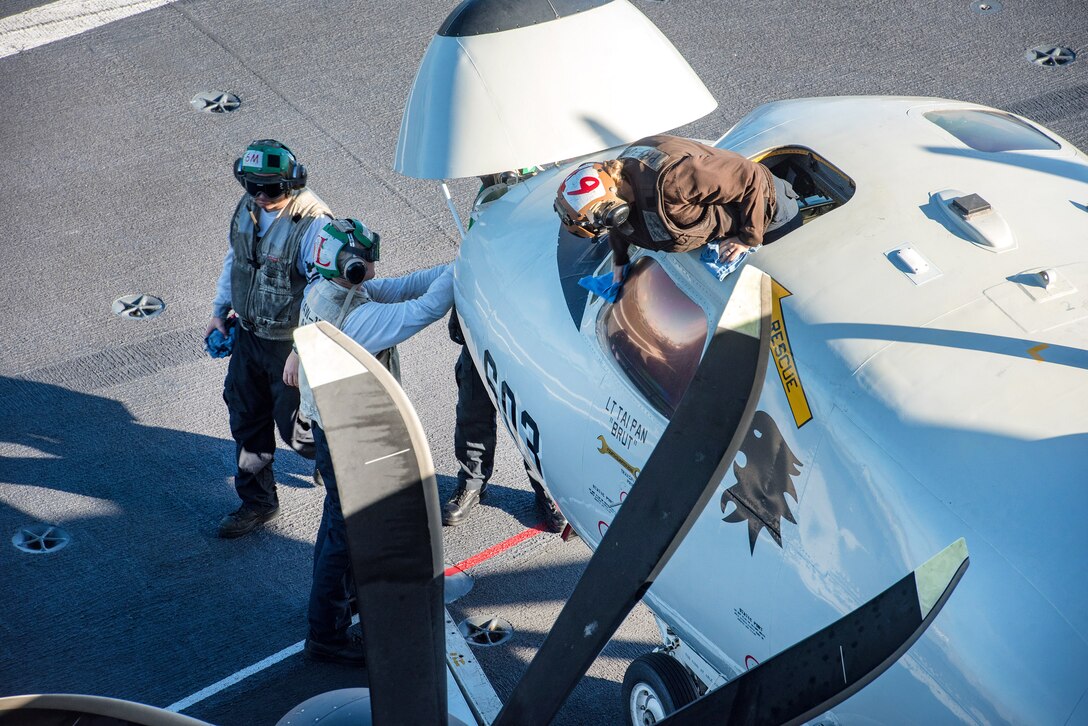 Sailors perform maintenance on an E-2C Hawkeye aircraft.