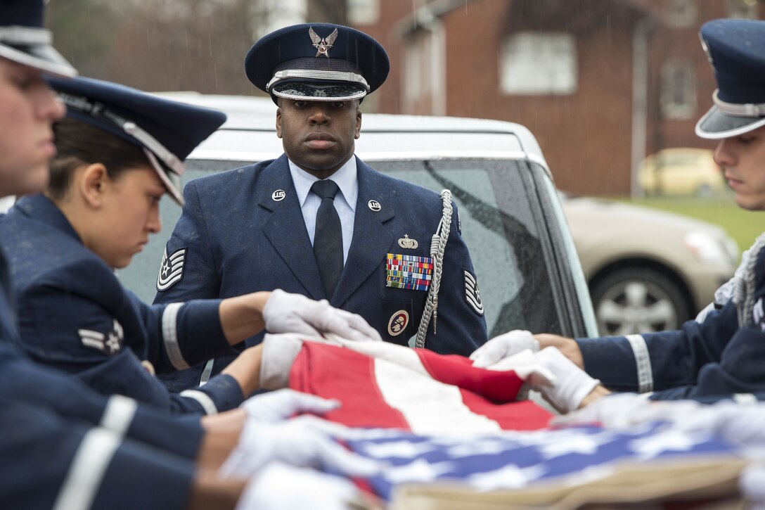 An airman watches the folding of an American flag.