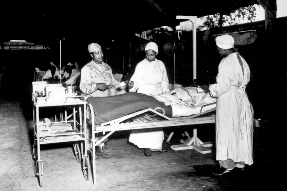 Nurses gather around the bed of a person.