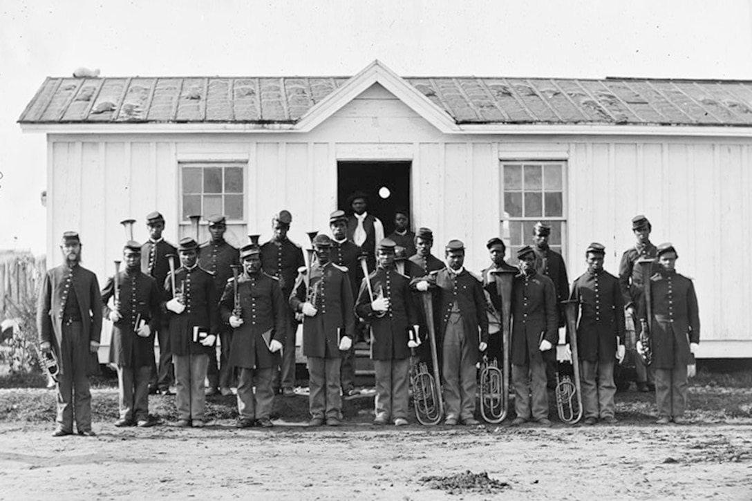 Rows of soldiers pose for a photograph outside of a building.