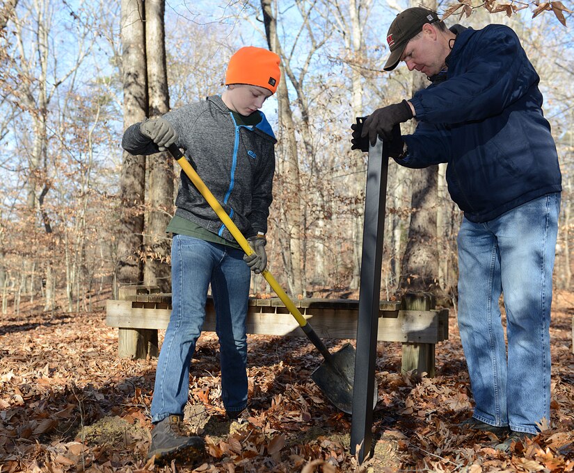 Nicholas Burney, left, age 13, Fort Eustis Boys Scouts Troop 45 member and son of U.S. Army Master Sgt. Nicholas Burney, 1st Battalion, 210th Aviation Regiment, 128th Aviation Brigade NCO and Fort Eustis Troop 45 scout master, and Don Calder, 733rd Civil Engineer Division environmental chief, install a post for educational environmental signs along the nature trail at Joint Base Langley-Eustis, Va., Jan. 20, 2018.