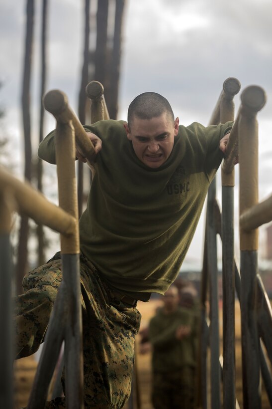 A Marines uses his arms to move down parallel bars.
