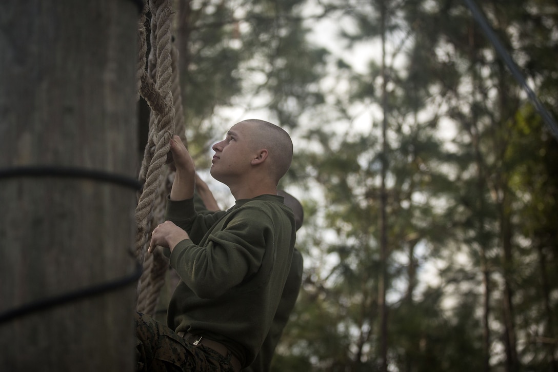 A Marine climbs up a rope ladder.