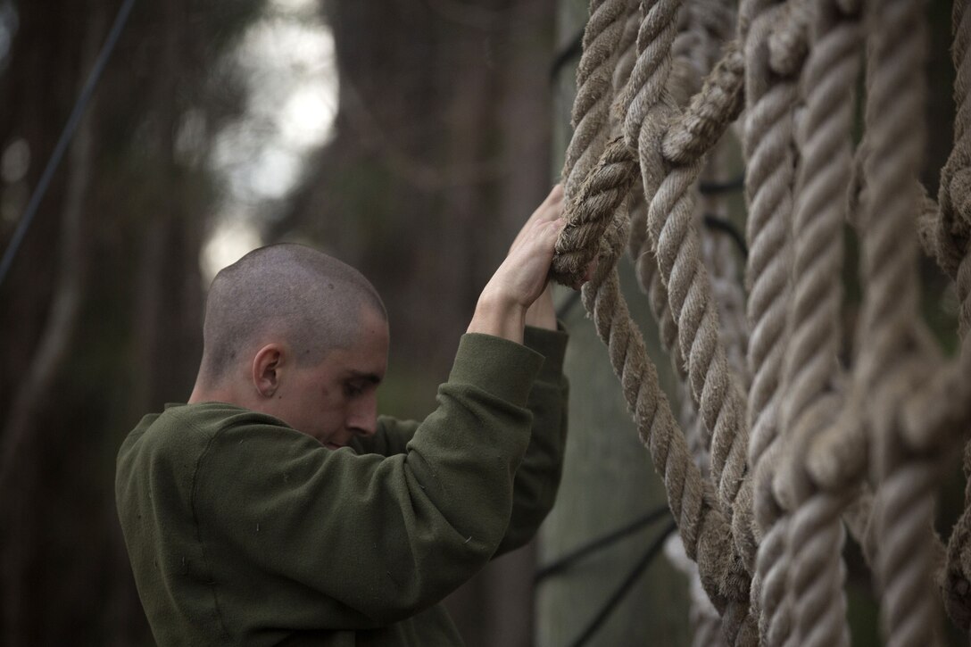 A Marine climbs a rope net.