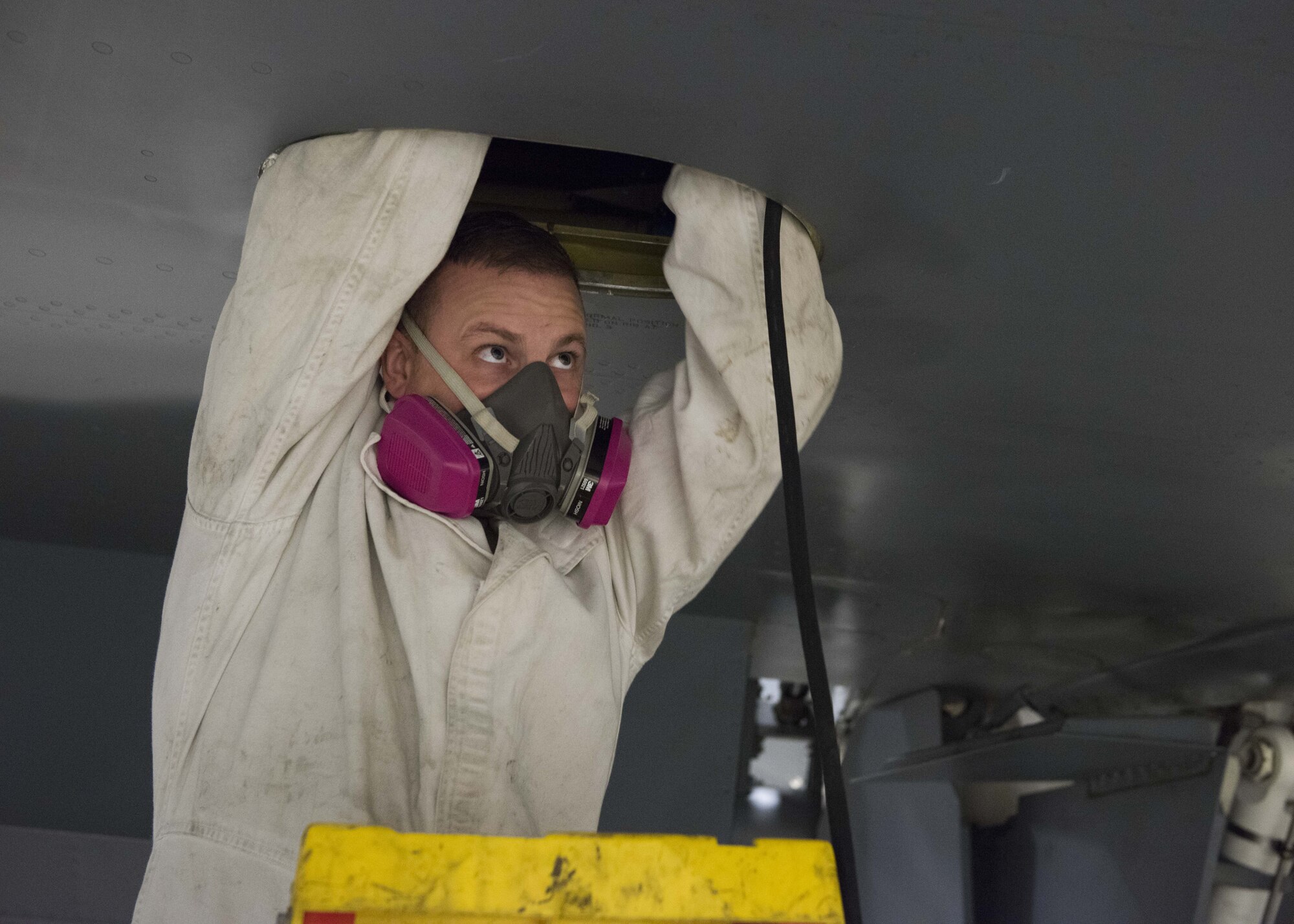 Master Sgt. Zach Kuno, 141st Maintenance Squadron, Aircraft Fuel Systems supervisor, enters a fuel tank on a KC-135 Stratotanker while wearing a respirator and anti-static suit at Fairchild Air Force Base, Washington, Nov. 21, 2017. The atmosphere in and around a fuel tank must be kept at safe levels of no more than 10 percent fuel vapor and oxygen levels between 19.5 and 23.5 percent to minimize health and fire risks. (U.S. Air Force photo/Senior Airman Ryan Lackey)
