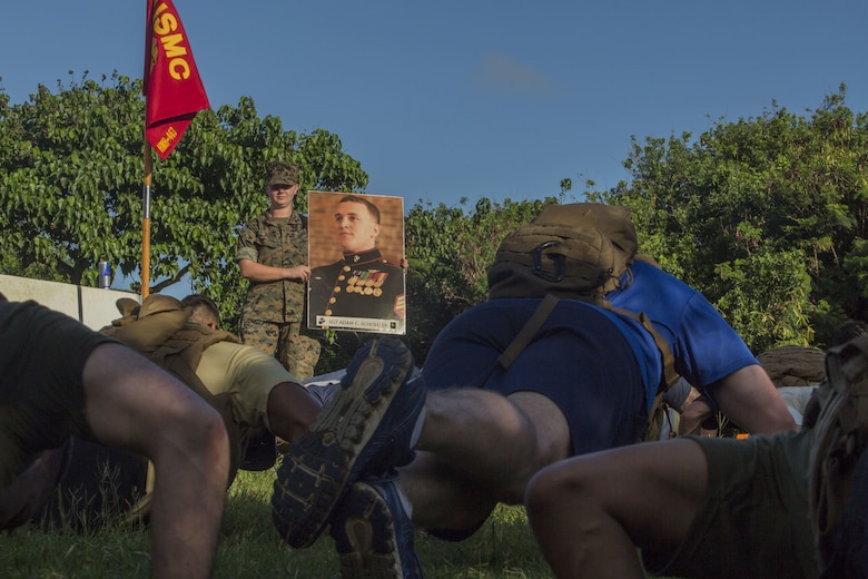 U.S. Marines with Marine Heavy Helicopter Squadron 463 (HMH-463), stop to exercise by a poster of Sgt. Adam Schoeller, one of the 12 Marines memorialized during a squadron hike, Jan. 11, 2018. The hike commemorated the Marines from the squadron who were lost in a CH-53E crash while conducting training operations in 2016. While the hike was a solemn reminder of those the squadron lost, it also served as an event to help celebrate the Marines’ lives and the proud traditions of HMH-463. (U.S. Marine Corps Photo by Lance Cpl. Luke Kuennen)