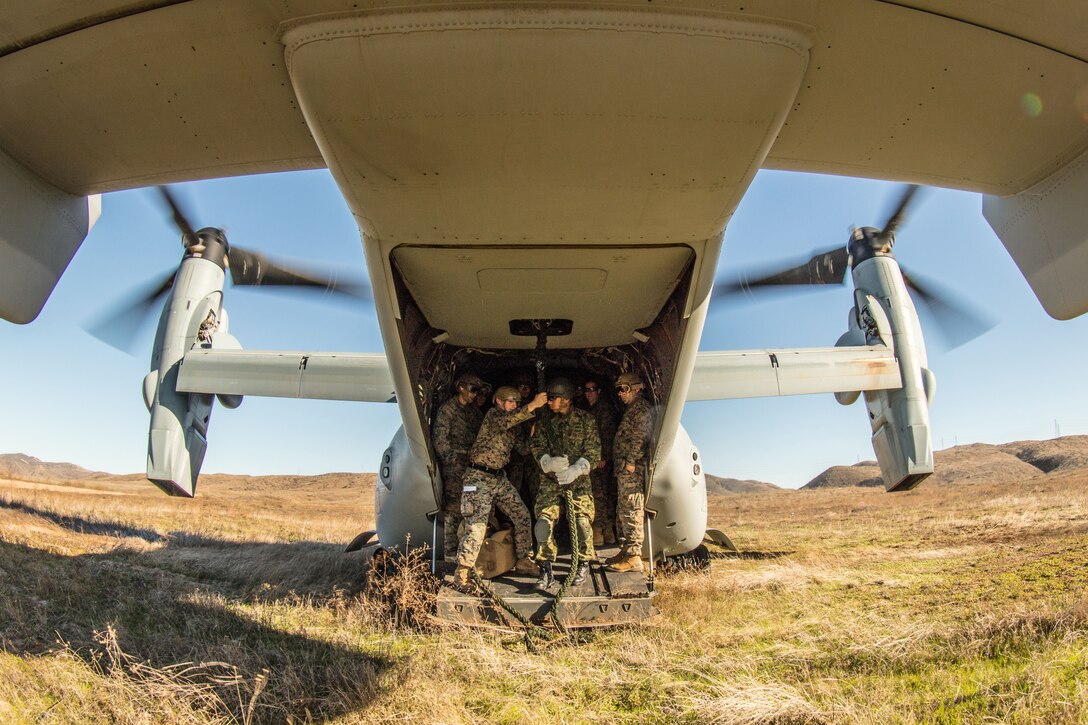 Marines stand in the back of an aircraft.