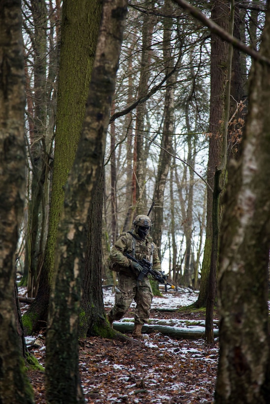 A soldier walks through the woods.