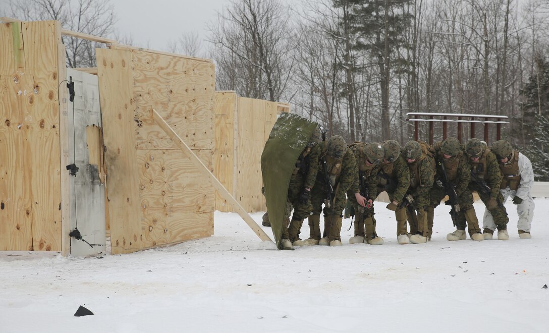 Marines with Company E, 4th Combat Engineer Battalion, 25th Marine Regiment, 4th Marine Division, take cover as they prepare for a charge to breach a building during exercise Nordic Frost at Camp Ethan Allen Training Site in Jericho, Vt., Jan. 19, 2018. The goal of Nordic Frost was to improve the unit’s environmental capabilities by giving them an introduction to cold weather training and testing their squad and fire team level defensive proficiency in an austere environment. (U.S. Marine Corps photo by Pfc. Samantha Schwoch/released)