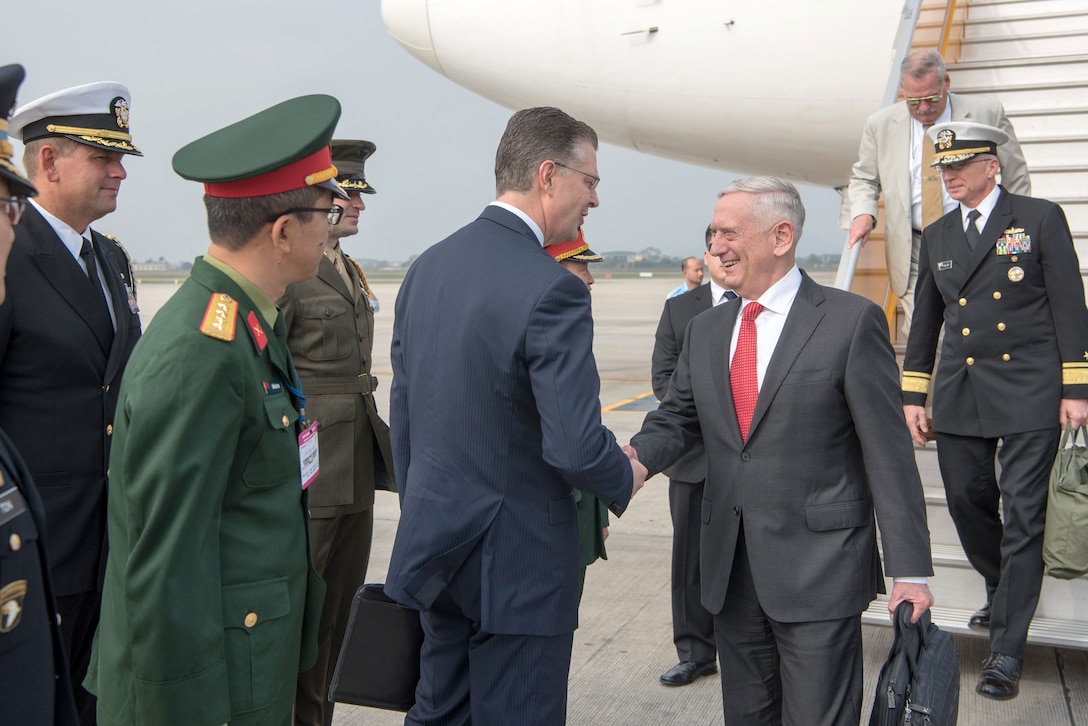 Defense Secretary James N. Mattis shakes hands with people near an aircraft.