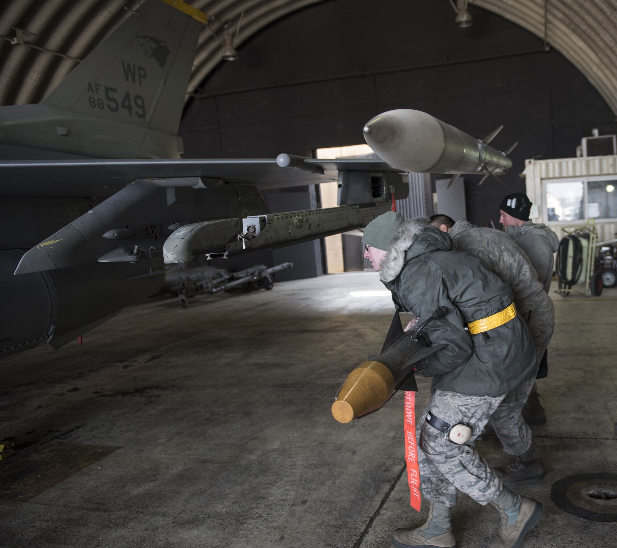 Three U.S. Air Force Airmen assigned to the 8th Aircraft Maintenance Squadron as weapons load crew members, work together to load an F-16 Fighting Falcon during an aircraft generation exercise at Kunsan Air Base, Republic of Korea, January 22, 2018. Members of load crews precisely and promptly loaded over ten aircraft in under 12 hours confirming the Airmen’s abilities to proficiently carry out a concept of operations. Aircraft generations are simulated on a regular basis to confirm the Wolf Pack’s capability maintain mission readiness at all times. (U.S. Air Force photo by Tech. Sgt. Josh Rosales)