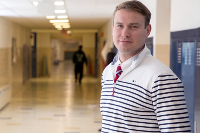 A man poses for a photograph in a hallway.