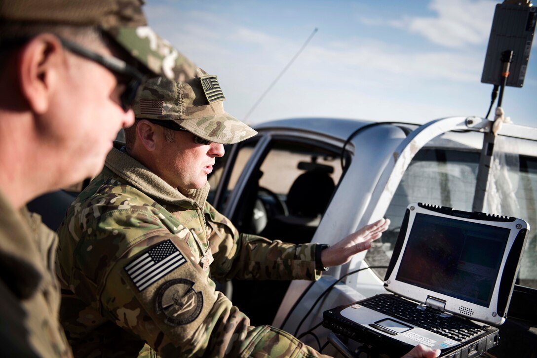 Air Force Tech Sgt. Matthew Coutts, right, demonstrates the capabilities of the Raven B Digital Data Link drone for Air Force Brig. Gen. Kyle Robinson, commander, 332nd Air Expeditionary Wing, in Southwest Asia.