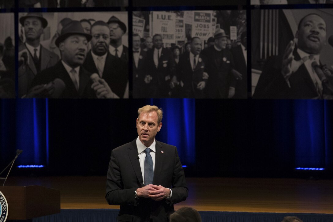 Deputy Secretary of Defense Patrick M. Shanahan speaking in front of three images of Dr. Martin Luther King Jr.