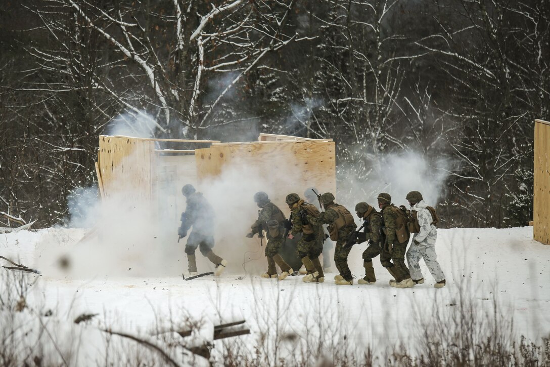 Marines breach and clear a building in a cold, mountainous environment.