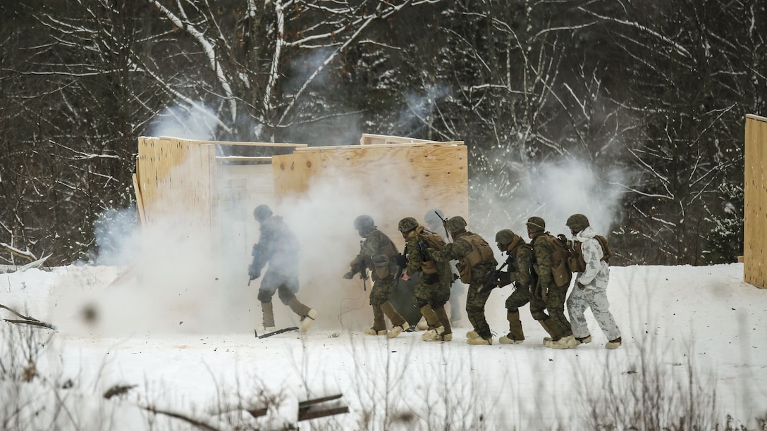 Marines breach and clear a building in a cold, mountainous environment.