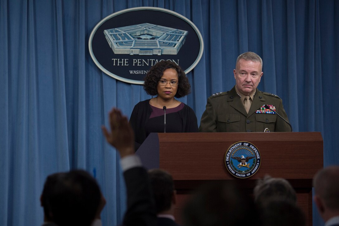 The chief Pentagon spokesperson and the Joint Chiefs director brief reporters behind a podium.