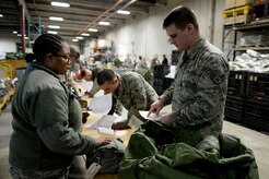 Tech. Sgt. Surnicke Graham, noncommissioned officer in charge of the 673d Logistics Readiness Squadron Individual Protective Equipment Element, discusses issue list with U.S. Air force Staff Sgt. Donald Steelfox, Jan. 17, 2018, at Joint Base Elmendorf-Richardson, Alaska. The 673d LRS/IPE is responsible for inspecting all chemical, biological, radiological, and nuclear IPE.
