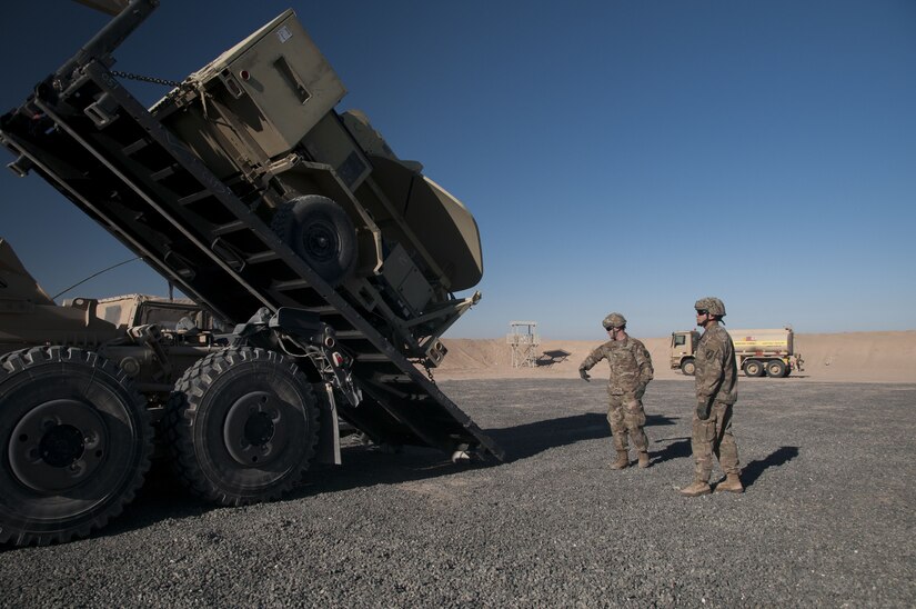 Spc. Aaron Harness, a motor transport operator, 1072nd Transportation Company, gives hand signals to a driver during the unloading of a satellite transportable terminal being lowered from a palletized load system during an emergency deployment readiness Jan. 12, 2018, at FOB Gerber on the Udairi Range Complex near Camp Buehring, Kuwait. The transportation unit moved signal equipment from Camp Buehring to the FOB as the 115th Signal Battalion practiced rapidly emplacing and connecting signal equipment in support of emergency operations.