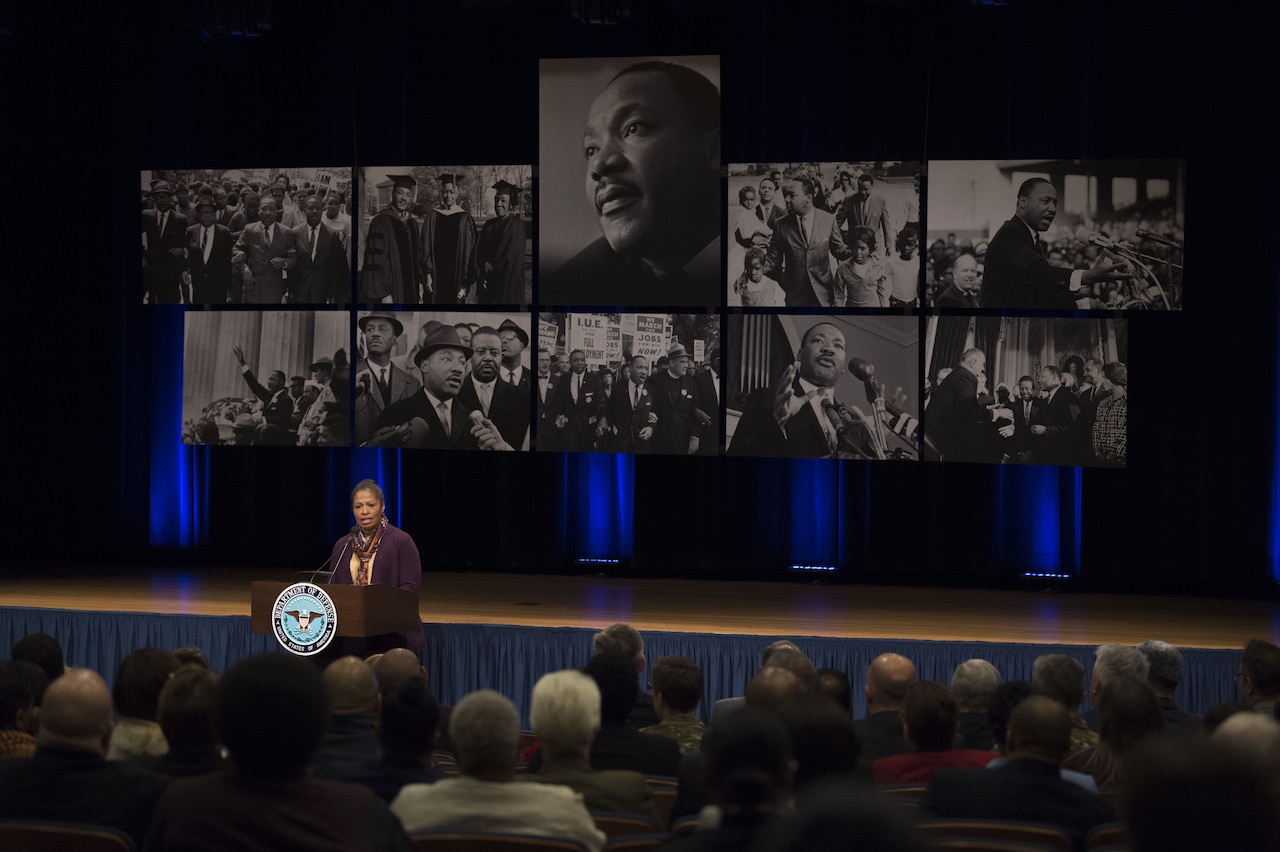 A retired soldier stands in front of eight images of Dr. Martin Luther King Jr.